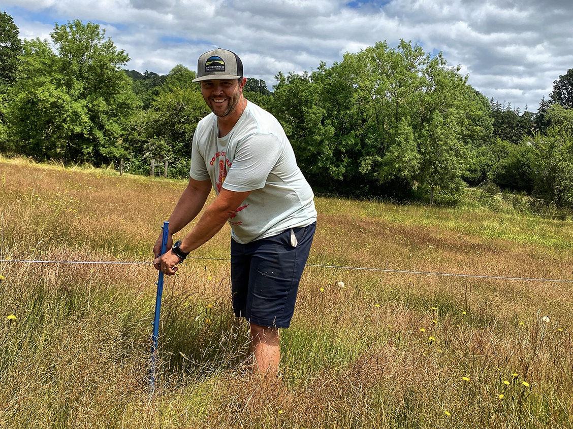 Tyler placing a wire fence outside in a field